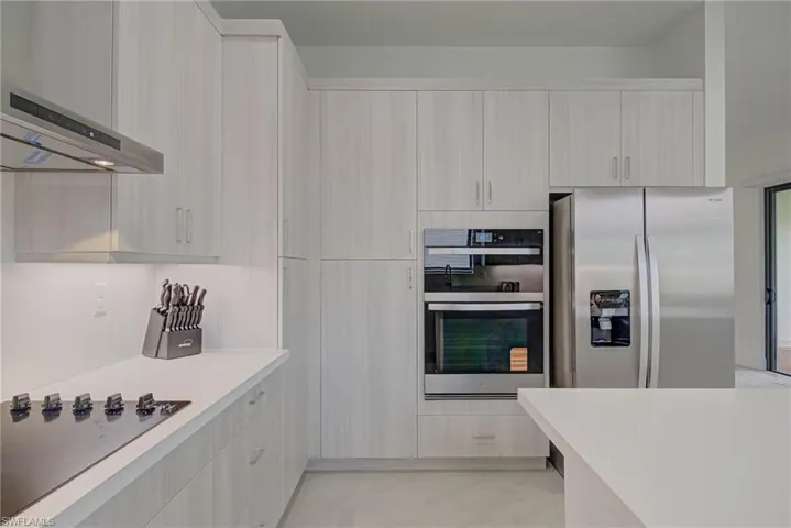 Kitchen with stainless steel appliances, wall chimney range hood, light countertops, and modern cabinets