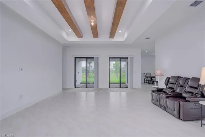 Living room with recessed lighting, tile patterned flooring, beam ceiling, and a raised ceiling