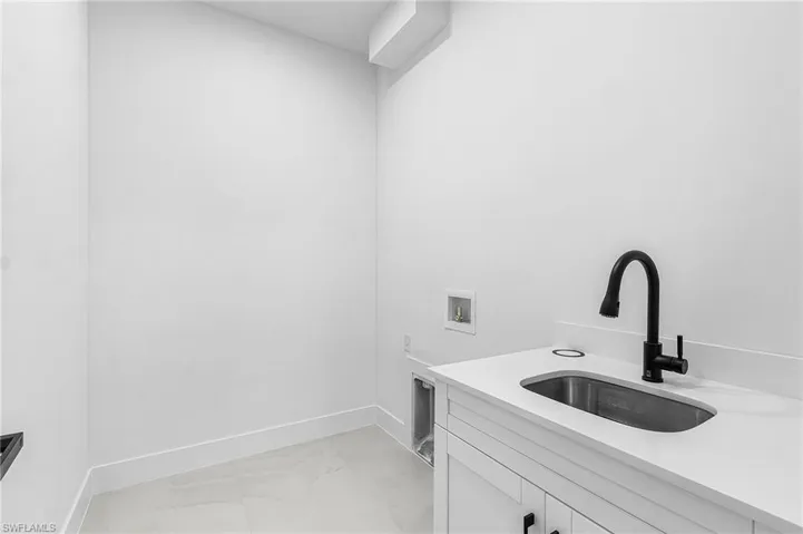 Washroom with washer hookup and light marble finish floors