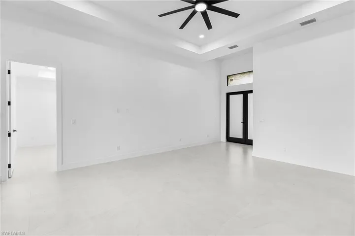 Spare room with a tray ceiling, recessed lighting, a ceiling fan, and a high ceiling