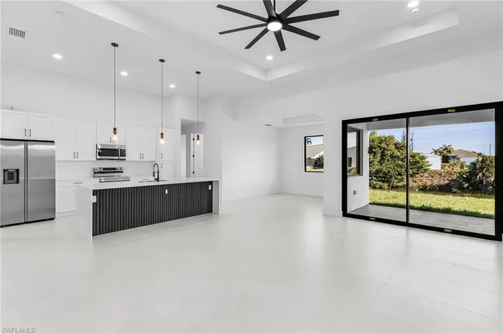 Unfurnished living room with a towering ceiling, a raised ceiling, recessed lighting, and a ceiling fan