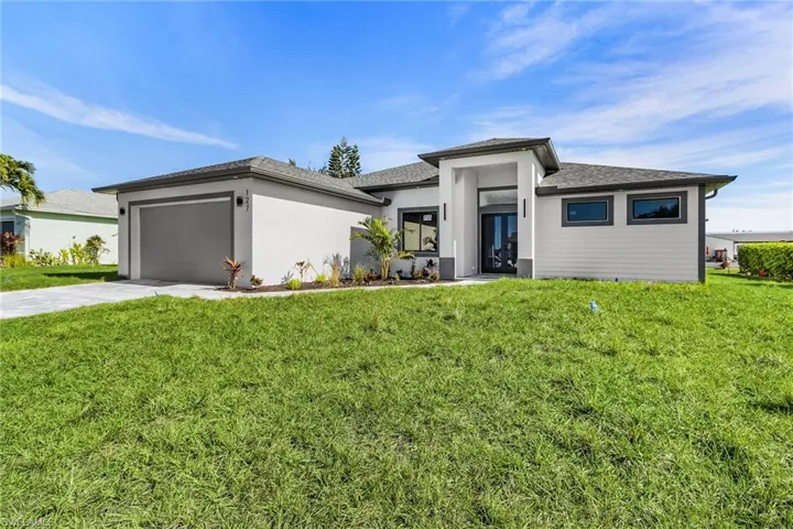 Prairie-style home with a front yard, concrete driveway, a garage, and stucco siding