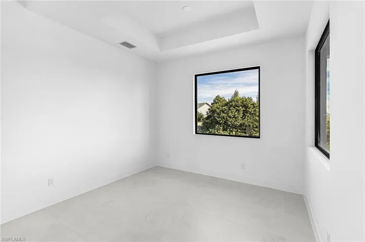 Unfurnished room with a tray ceiling and finished concrete floors