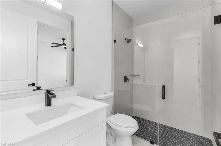 Full bathroom with vanity, a stall shower, and ceiling fan