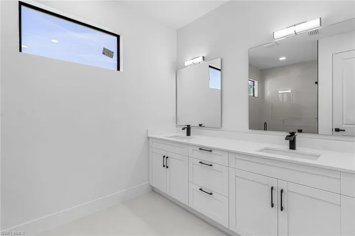Full bath with double vanity, concrete flooring, and a shower stall