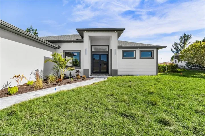 Doorway to property with a lawn, stucco siding, and a shingled roof