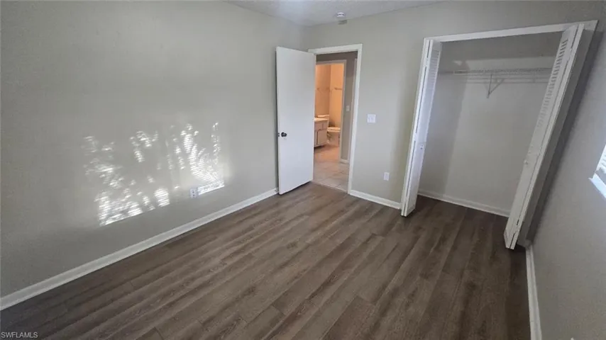 Unfurnished bedroom featuring dark wood-style flooring, a closet, and a textured ceiling
