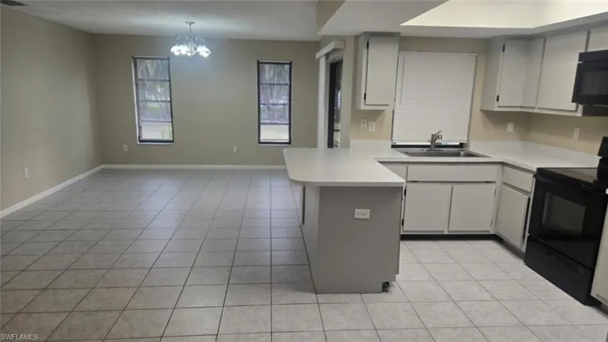 Kitchen with black appliances, a peninsula, light countertops, pendant lighting, and a textured ceiling