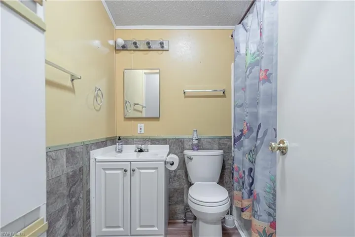 Bathroom featuring vanity, tile walls, a textured ceiling, and toilet