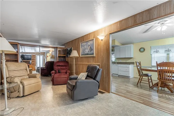 Living room featuring ceiling fan, a wealth of natural light, and wooden walls