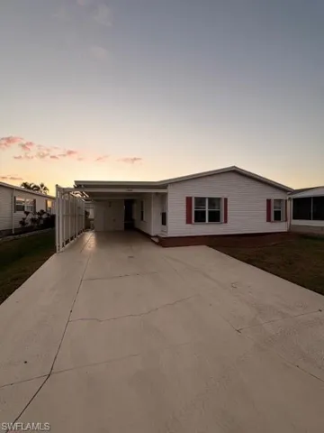 View of front of house featuring double-wide driveway, a carport, and a lawn