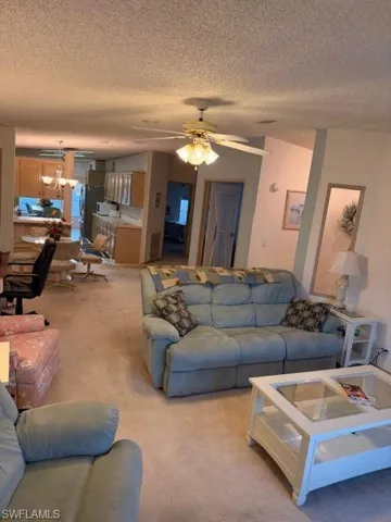 Living area with carpet floors, ceiling fan, and a textured ceiling