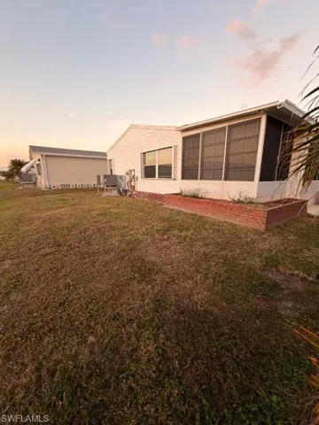 Back of house at dusk featuring a sunroom and a yard