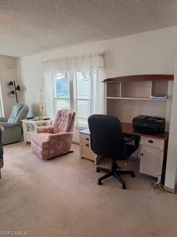 Office space with a textured ceiling and light colored carpet