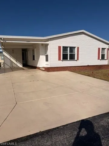 Back of property with an attached carport and driveway