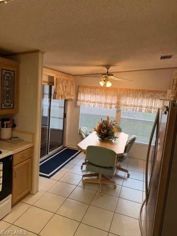 Eat in kitchen featuring a textured ceiling, tile floors, ceiling fan, and vaulted ceiling