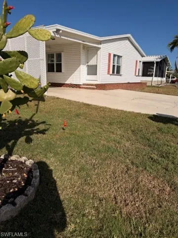 Rear view of house featuring a lawn, driveway, and entry steps