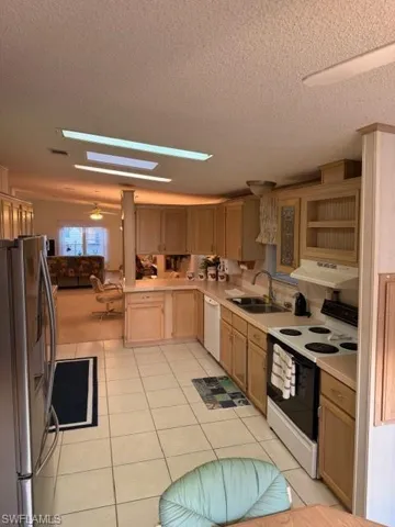 Kitchen with range, light countertops, fridge, a skylight, and a textured ceiling