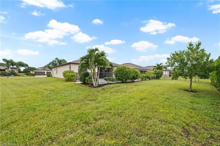 Expansive grassy lawn with mature landscaping and a screened-in lanai