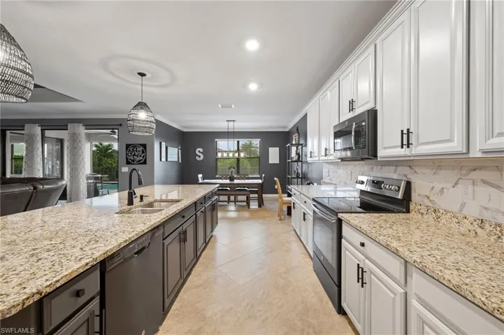 Kitchen featuring an expansive island with a double basin sink, light-toned countertops, tile flooring, and light perimeter cabinetry