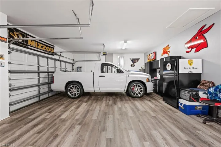 Garage featuring a roll-up door, wood-finish flooring, and built-in cabinetry