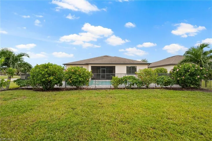 Expansive green lawn with mature landscaping, featuring a screened-in rear patio and an in-ground swimming pool