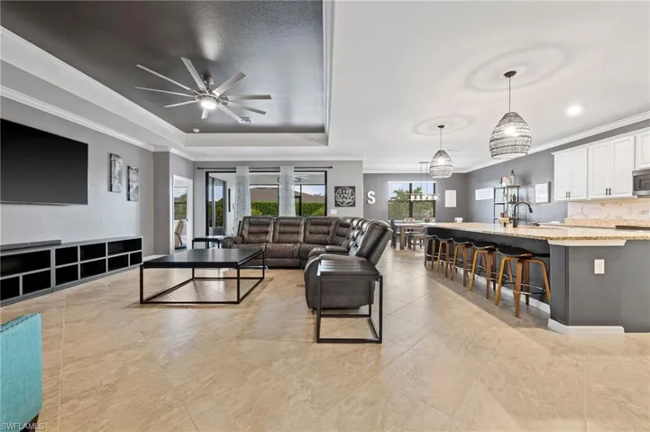 Expansive open-concept living area, tray ceiling custom painted, featuring Tile Floors, and a large kitchen island with seating
