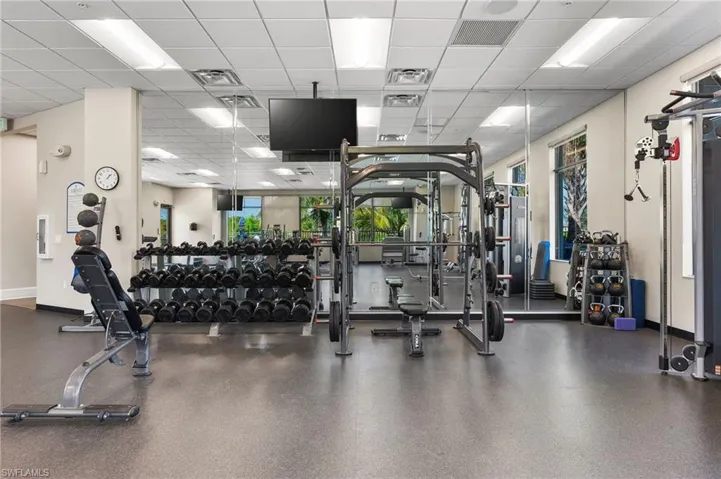 Fitness center featuring extensive mirrored walls, recessed lighting, and rubber flooring