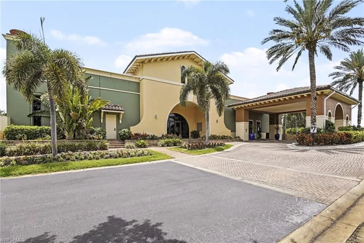 Mediterranean-inspired architecture featuring a terracotta-tiled roof, a porte-cochère entrance, and mature palm trees