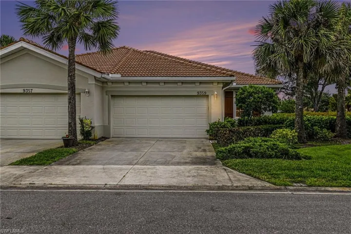 Mediterranean-style residence featuring a tile roof, stucco exterior, attached garage, well-maintained landscaping, and mature palm trees