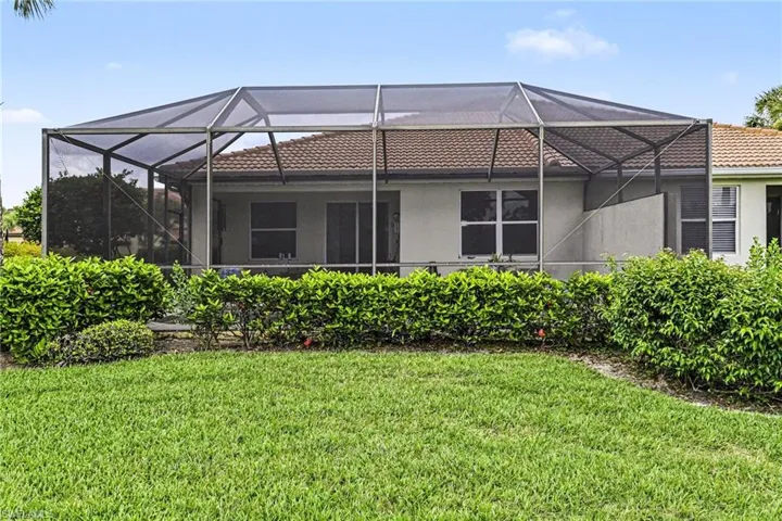 Screened patio enclosure with a terracotta tile roof, sliding glass doors, and manicured shrubbery