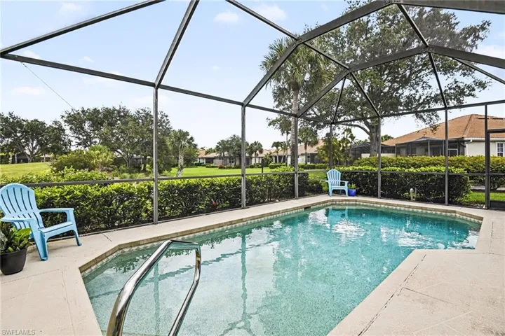 Screened pool area featuring a rectangular pool with a built-in step, handrail, and surrounding paver decking