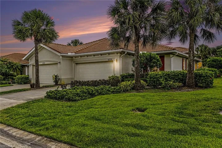 Exterior stucco residence featuring a tile roof, dual garage doors, and mature palm trees