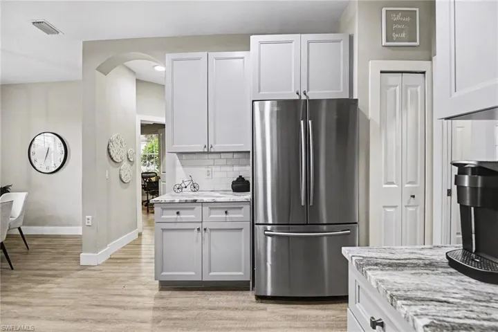 Contemporary kitchen cabinetry in a light finish, complemented by a stainless steel refrigerator and patterned countertops