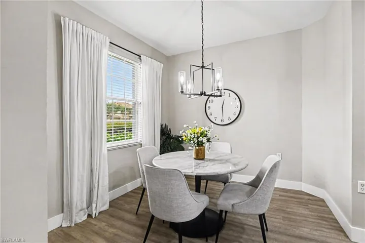 Dining area featuring wood-finish flooring, a modern linear chandelier, and a double-pane window with blinds