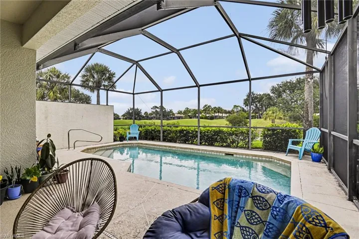 Screened-in pool deck featuring a freeform swimming pool with integrated steps and handrail