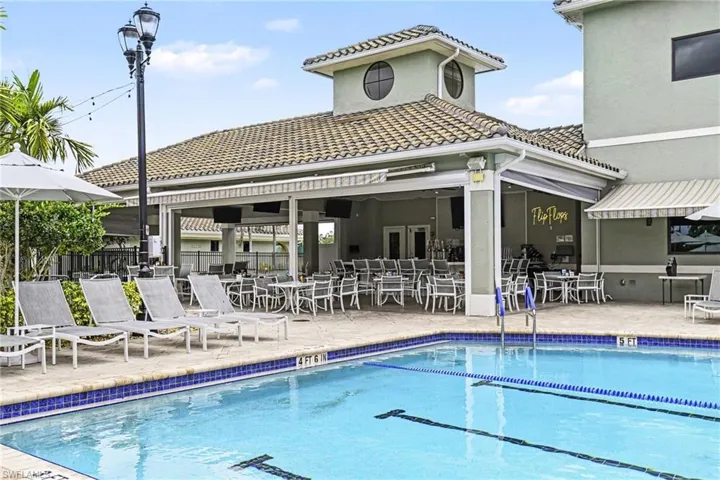 Resort-style pool area featuring a blue-tiled swimming pool and surrounding paved deck