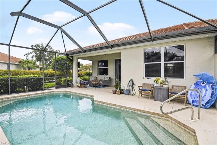 Screened-in pool area featuring a rectangular pool with integrated steps, stainless steel handrail, and a surrounding paver deck