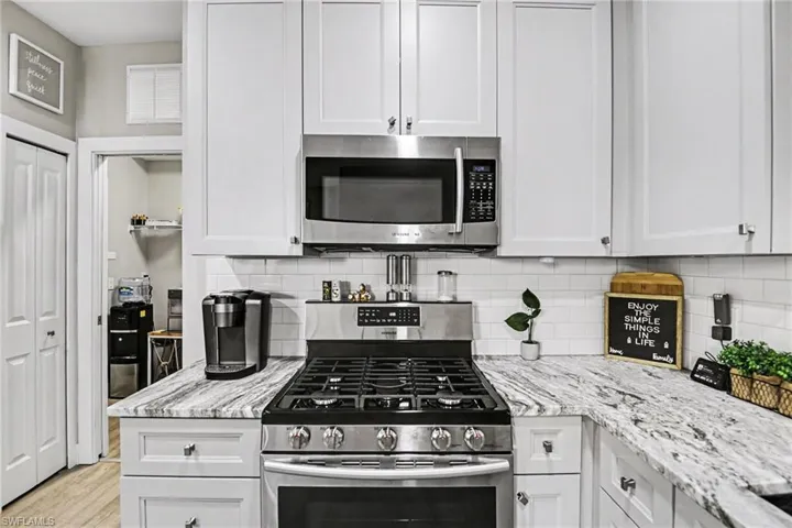 Modern kitchen featuring white shaker cabinetry, stainless steel appliances, a gas range, white subway tile backsplash, and stone-finish countertops