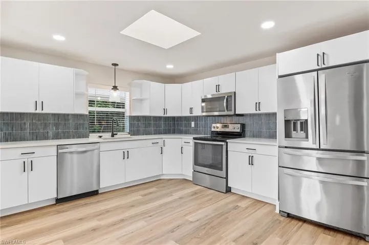 Kitchen with open shelves, appliances with stainless steel finishes, decorative light fixtures, white cabinets, and recessed lighting