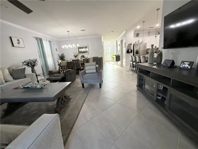 Living area featuring ornamental molding, light tile patterned floors, hanging lights, and a ceiling fan