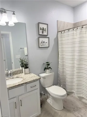 Bathroom with a shower with shower curtain, vanity, light tile patterned floors, and a textured wall