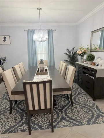 Dining room featuring ornamental molding, hanging lights, and light tile patterned flooring