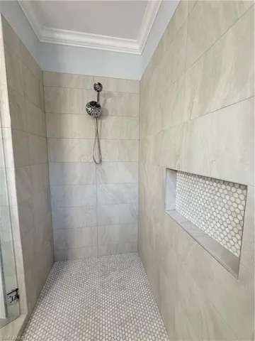 Bathroom with tiled shower and ornamental molding