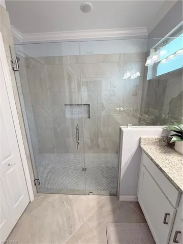Full bath featuring vanity, a stall shower, and ornamental molding