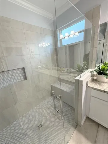 Bathroom with vanity, a stall shower, crown molding, and light tile patterned floors