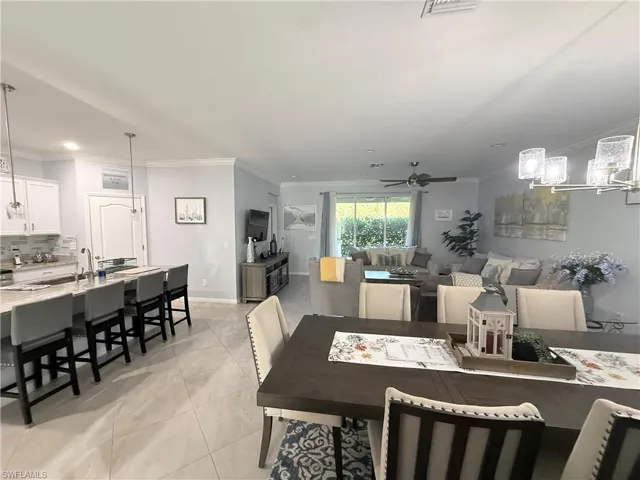 Dining space featuring ornamental molding, ceiling fan, light tile patterned floors, and suspended lighting