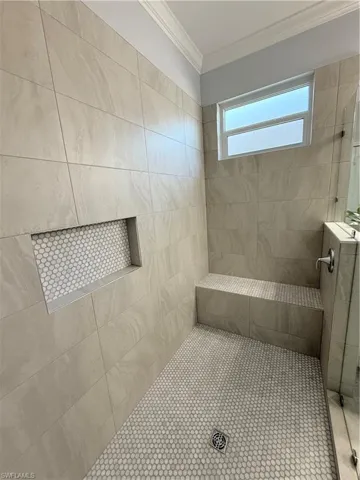 Full bath featuring a tile shower and ornamental molding