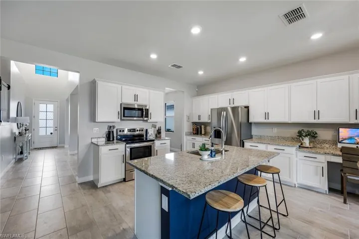 Kitchen featuring an island with sink, white cabinets, a breakfast bar area, and stainless steel appliances