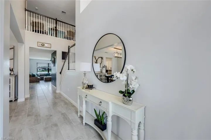 Hallway featuring a towering ceiling and light tile floors